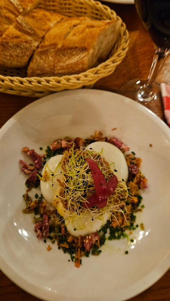 Plato en un bistró de París con huevos cocidos, hierbas y guarniciones, con pan y vino en la mesa.