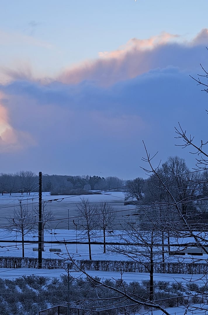 Ηλιοβασίλεμα με παστέλ ουρανό πάνω από παγωμένη λίμνη.