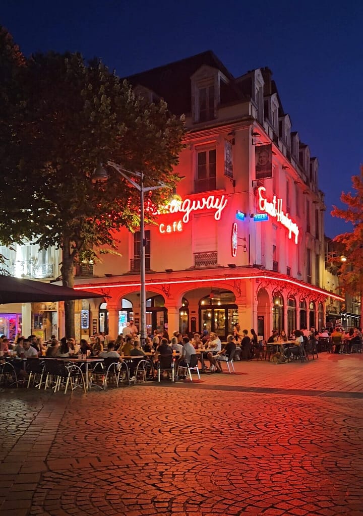 Evening terraces in central Reims with busy cafés and restaurants, Mediterranean-style night atmosphere.