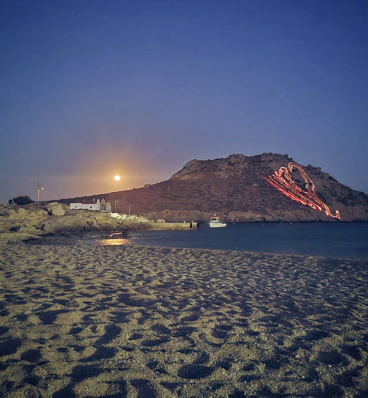 Agia Anna Beach in Mykonos at night with moonlight over the sea and rocky coastline