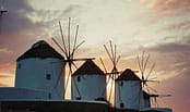 Mykonos windmills at sunset with orange sky and white silhouettes in Chora